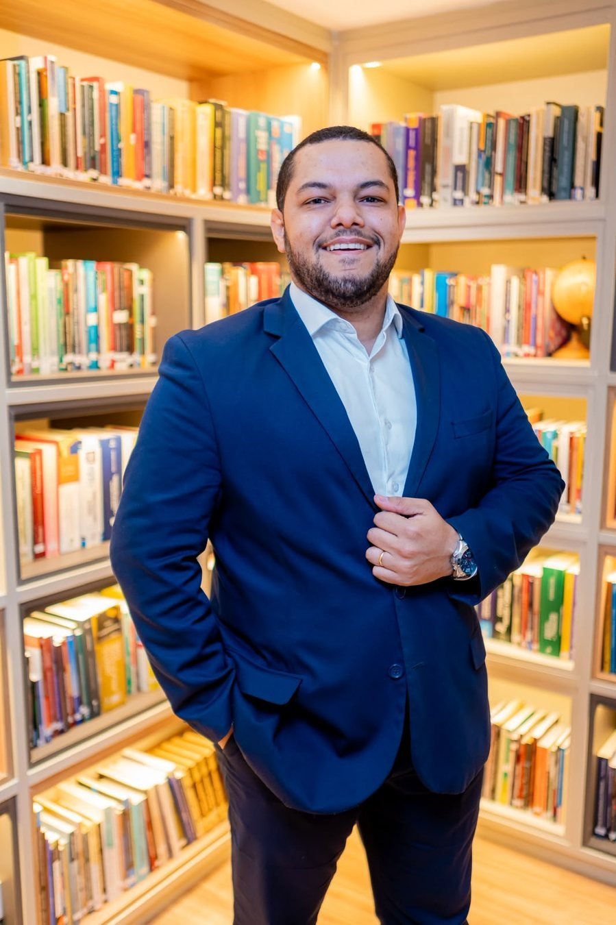 Dr. Vinícius Honorato em frente a uma estante de livros jurídicos